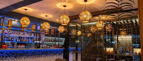 A bar area with wicker furniture and hanging light fixtures.