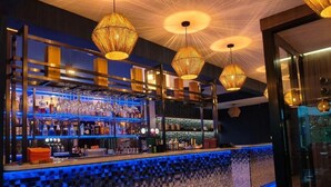 Un bar avec un mur recouvert de mosaïques et des luminaires suspendus.