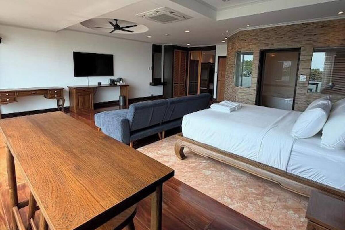 Un dormitorio moderno con una mesa de comedor de madera, un sofá y una cama con cabecera.