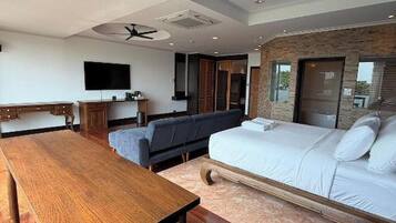 A modern bedroom with a wooden dining table, a sofa, and a bed with a headboard.