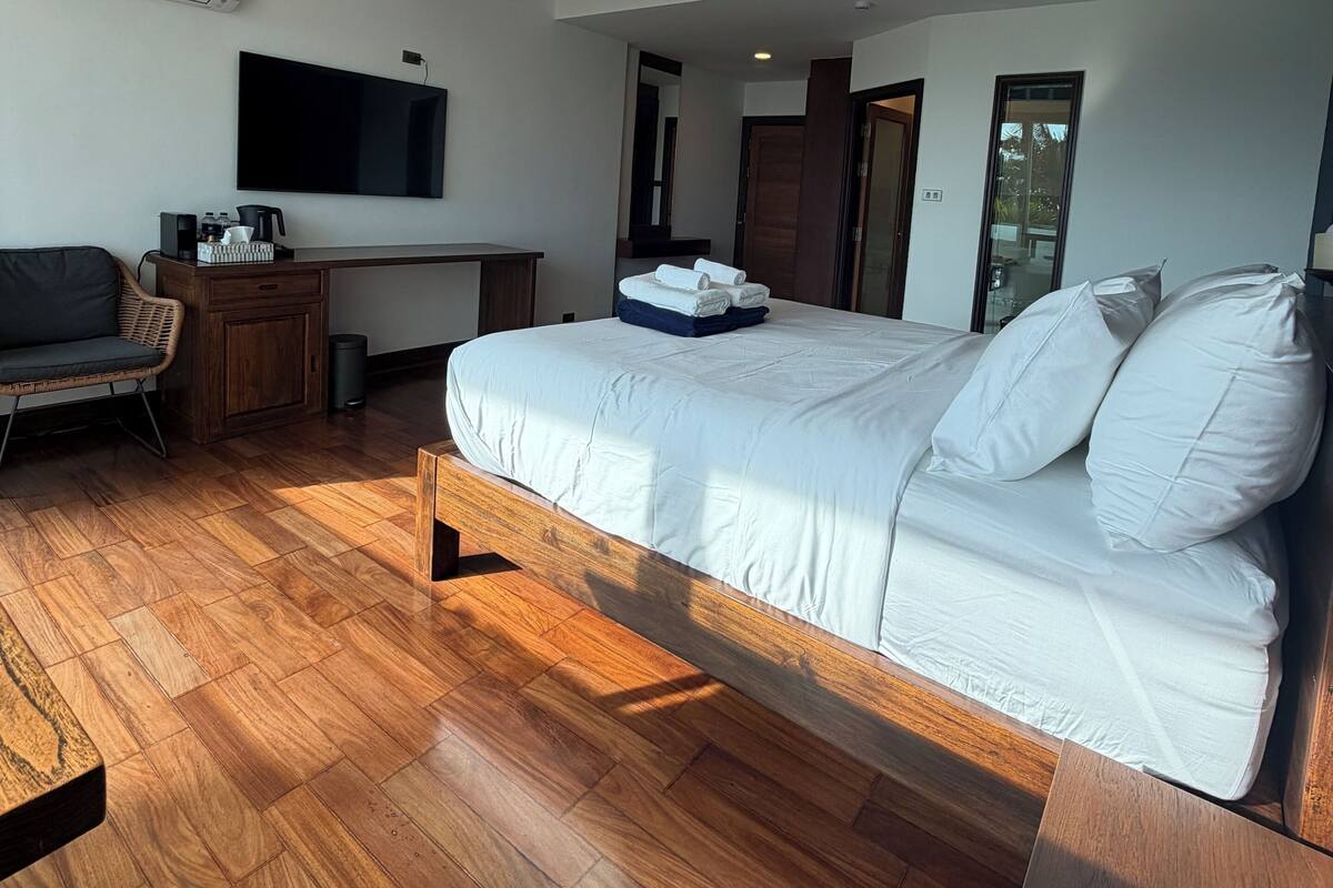 Un dormitorio moderno con una cama grande, un televisor, un escritorio y una silla.