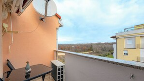 Ein Balkon mit Glastisch, einer Klimaanlage und einer Satellitenschüssel.