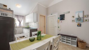 Eine moderne Küche mit weißen Schränken, einem Kühlschrank und einem Essbereich mit Tisch für zwei Personen.