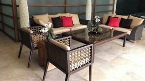 A modern living room with a sofa set, a coffee table, and two chairs with woven backs. - Spacious 2-BR apartment in the best location! (San Rafael de Escazú)