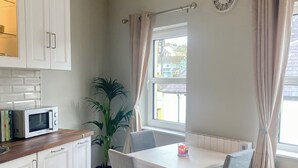 Une cuisine moderne avec des meubles blancs, un four à micro-ondes et un coin repas comprenant une table et des chaises.
