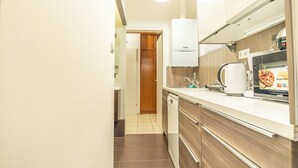 A compact kitchen with a dishwasher, a coffee maker, and a microwave. - Cozy 2BR City Retreat Central Location (Vienna)