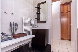 A bathroom with a white sink, dark wooden cabinets, a mirror, and a towel rack. - Cozy 2BR City Retreat Central Location (Vienna)