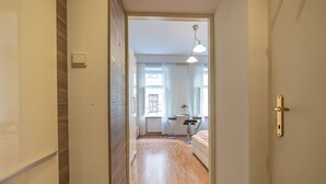 A hallway leading to a bedroom with a bed, bedside table, and lamp. - Cozy 2BR City Retreat Central Location (Vienna)