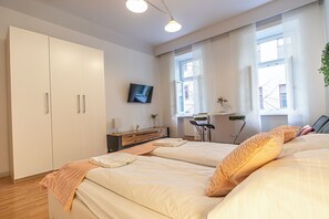 A bedroom with two beds, a TV, a desk, and a window with blinds. - Cozy 2BR City Retreat Central Location (Vienna)
