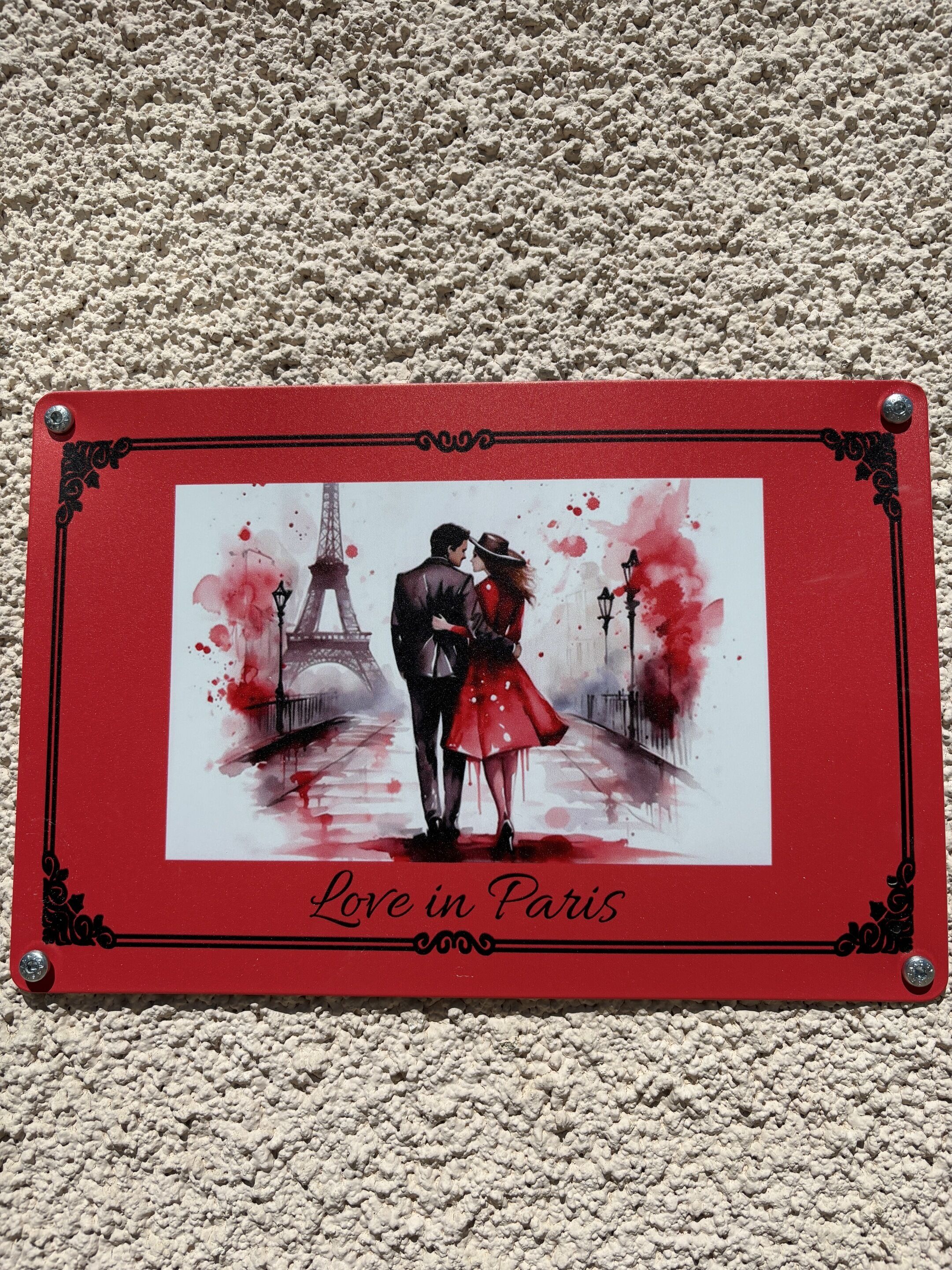 Une photographie encadrée représentant un couple devant la Tour Eiffel, avec la légende : « L’amour à Paris ».