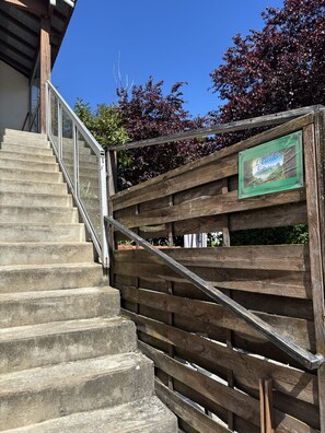 A wooden staircase with a metal railing leading to a wooden fence with a sign.