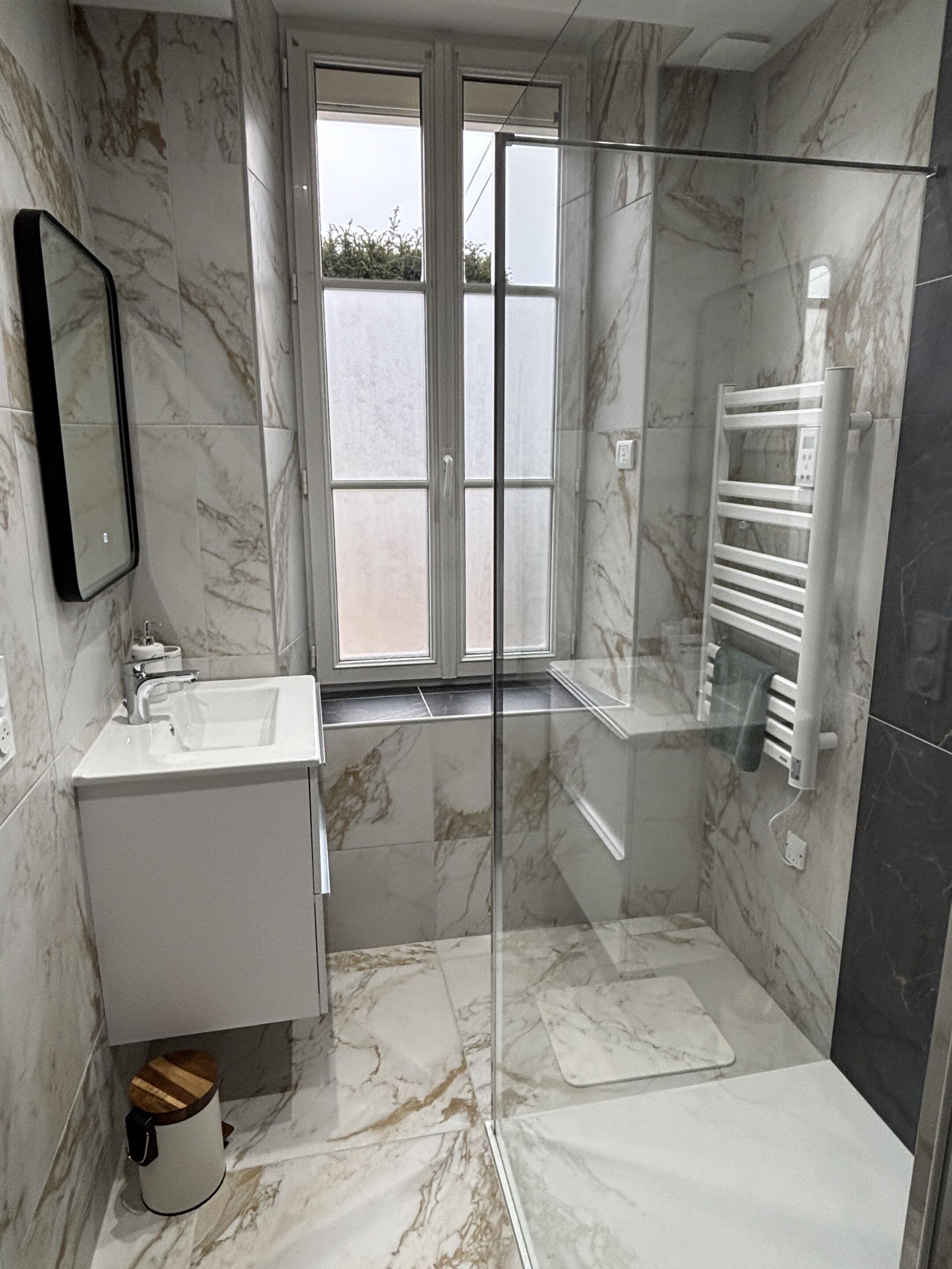 Une salle de bain moderne avec une douche à parois de verre, un lavabo et un porte-serviettes.