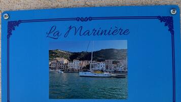Un cartel enmarcado con el texto 'La Mariniera' y una foto de un pueblo costero con edificios y barcos.