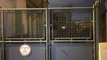 A metal gate with a sign that reads "ATTENTION AU CHIEN" (Attention Dog).
