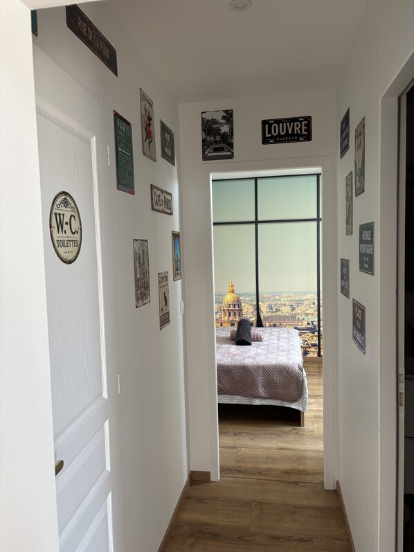 A hallway with a bed in the background, a view of a cityscape, and various signs on the walls.