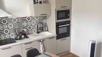 A compact kitchen with a coffee machine, a sink, and a microwave.