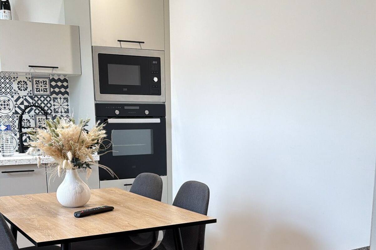Une cuisine moderne équipée d’un four à micro-ondes, d’un four traditionnel et d’un coin repas avec une table et des chaises.