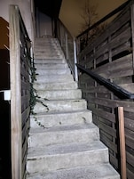 A staircase with stone steps and wooden railings, leading to an upper floor.
