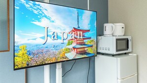 Ein Fernseher zeigt eine malerische Ansicht von Japan mit einer traditionellen Pagode, vor einem Hintergrund aus Herbstlaub und blauem Himmel.