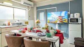 Eine moderne Küche mit Essbereich, inklusive Fernseher, der eine japanische Szene zeigt, Kühlschrank und Mikrowelle.