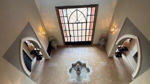 A spacious atrium with a central fountain, a decorative window, and two seating areas with lamps.