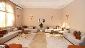 A spacious living room with a beige sofa set, a coffee table, and a potted plant.