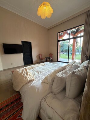 Quarto com uma cama grande, televisão na parede e janela com vista para o exterior.