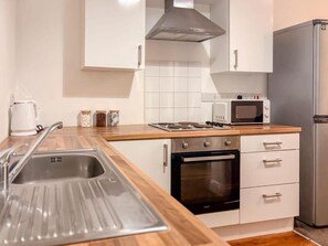 Eine kleine Küche mit Spüle, Herd, Backofen, Mikrowelle und Kühlschrank.