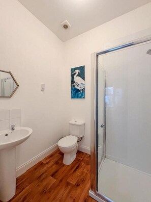 Ein Badezimmer mit Waschbecken, Toilette und einer Duschkabine aus Glas.