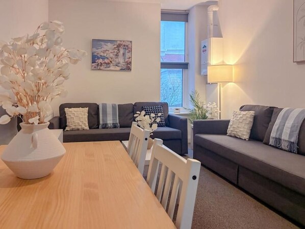 Ein modernes Wohnzimmer mit einem Holzesstisch, zwei Sofas und einem großen Fenster.