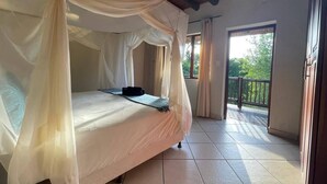 Une chambre à coucher avec un lit recouvert d’un dais blanc, une petite table et une vue sur l’extérieur grâce à une porte coulissante.