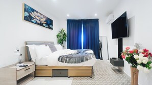 Un dormitorio moderno con cama, mesita de noche, televisor y un cuadro.