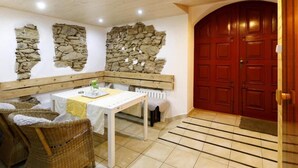 Comedor con mesa, sillas, paredes de piedra y una puerta roja.