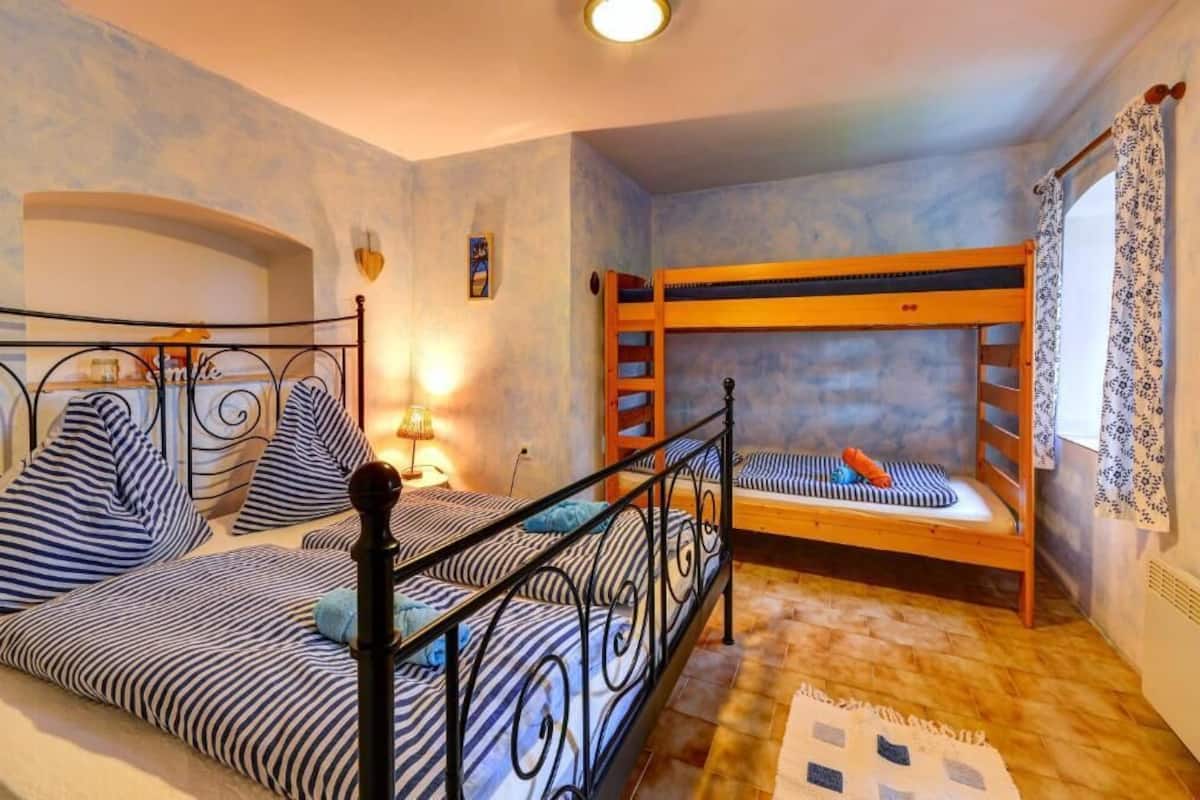 A bedroom with two beds, one with a metal frame and the other with a wooden frame, both with striped bedding.