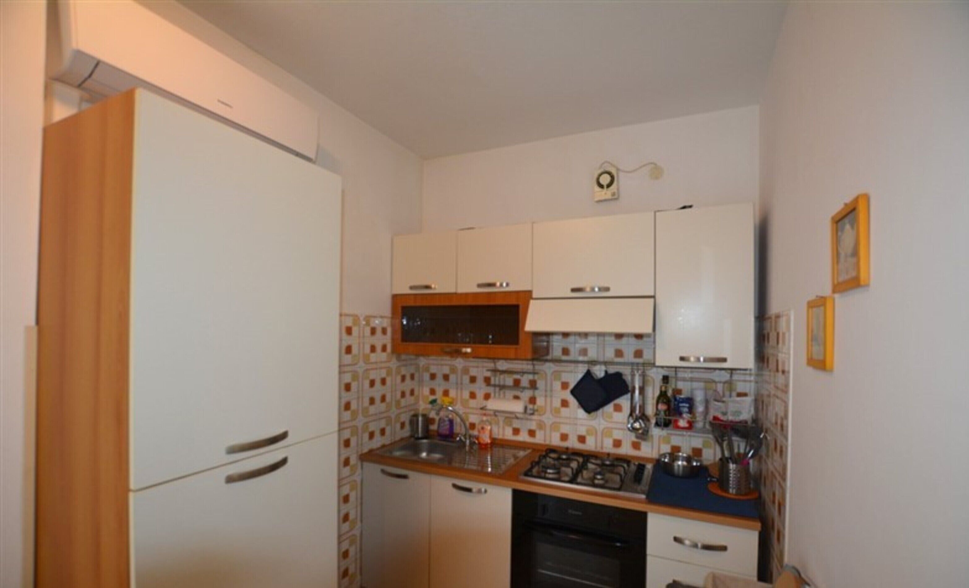 A compact kitchen with white cabinets, a microwave, a gas stove, and a tiled backsplash.