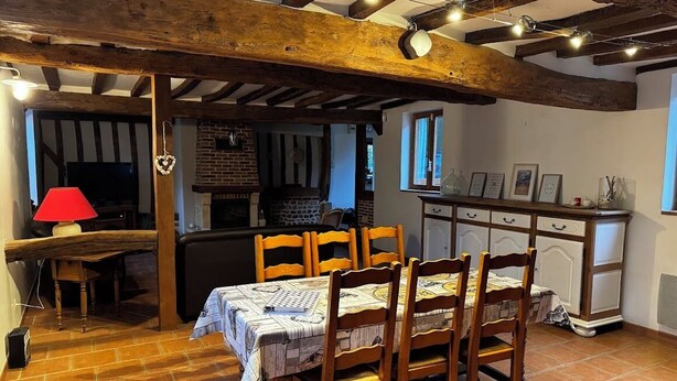 A dining area with a table set for four, wooden chairs, a red lamp, and a brick fireplace. - L écrin de l aube  (Grainville-la-Teinturière)