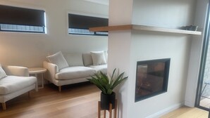 Una sala de estar moderna con chimenea, un sofá, una mesita y una planta en maceta.