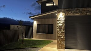 Una casa moderna con fachada de piedra, un ventanal grande y un camino de entrada bien iluminado durante la noche.