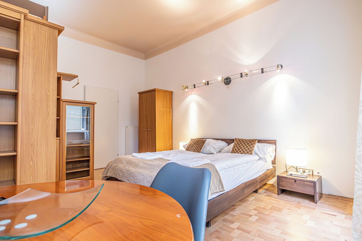 Ein Schlafzimmer mit Bett, Nachttisch, Lampe, Kleiderschrank und Schreibtisch mit Stuhl.