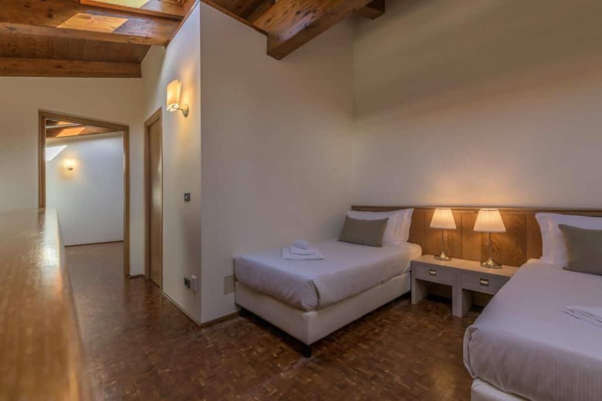 Quarto com duas camas, piso de madeira e teto de madeira.