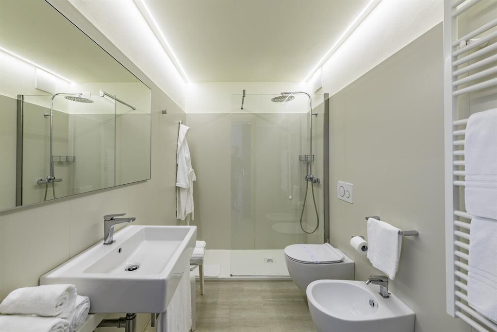 Un baño moderno con ducha de vidrio, lavamanos independiente y bidé.