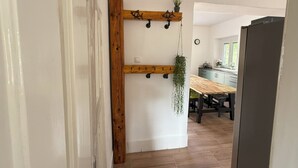 A kitchen with a wooden table and chairs, a hanging plant, and a clock on the wall.