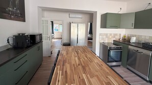 A modern kitchen with a wooden island, stainless steel appliances, and green cabinets.
