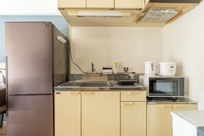 Eine kompakte Küche mit einem Edelstahlkühlschrank, einer Mikrowelle und einer Kaffeemaschine auf der Arbeitsfläche.