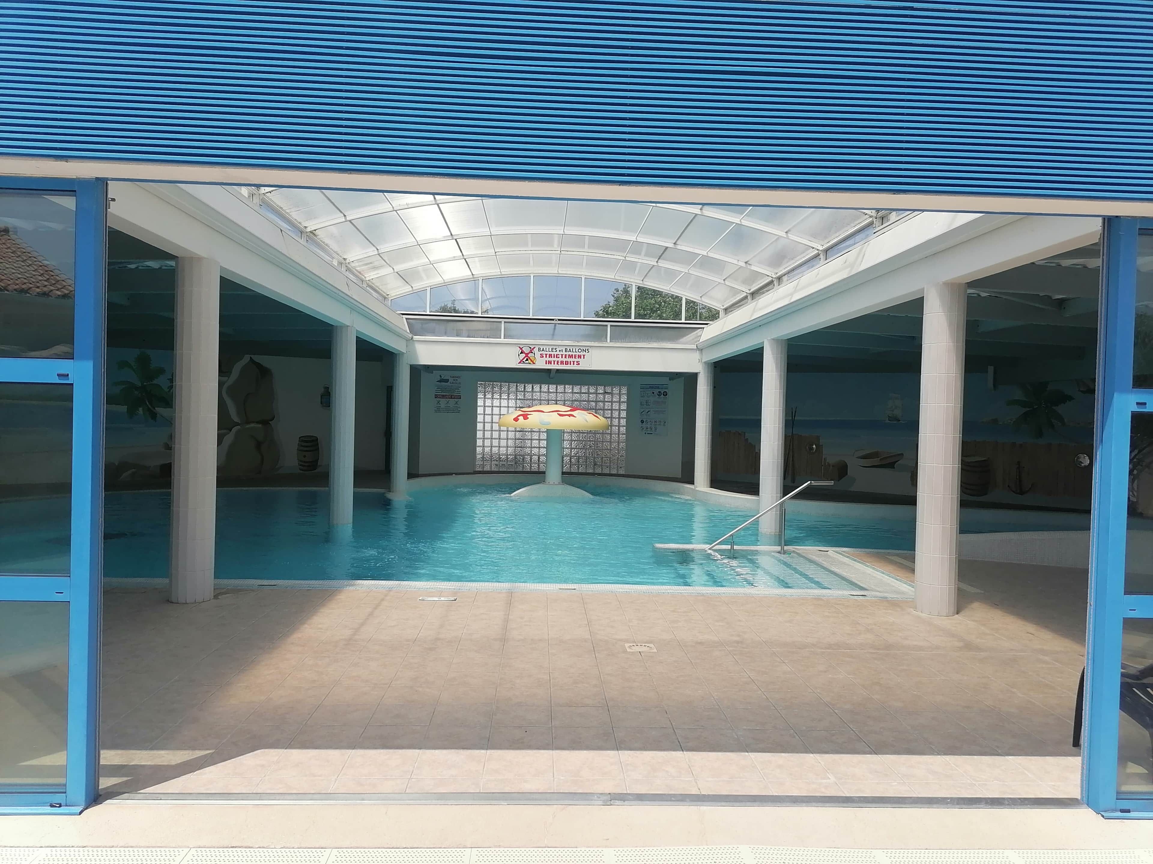 An indoor swimming pool with a glass ceiling, a lifeguard stand, and a sign for 'BALLS & BALLS STRATEGEM INTERDITIONS'.
