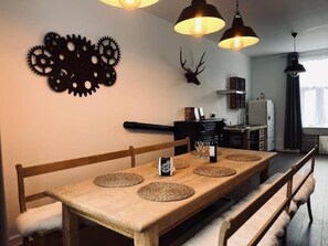 Uma área de refeições com mesa de madeira, bancos e um detalhe decorativo na parede.