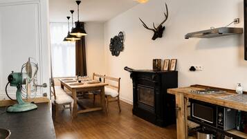 Una cucina moderna con zona pranzo, pavimento in legno, camino e testa di cervo appesa al muro.