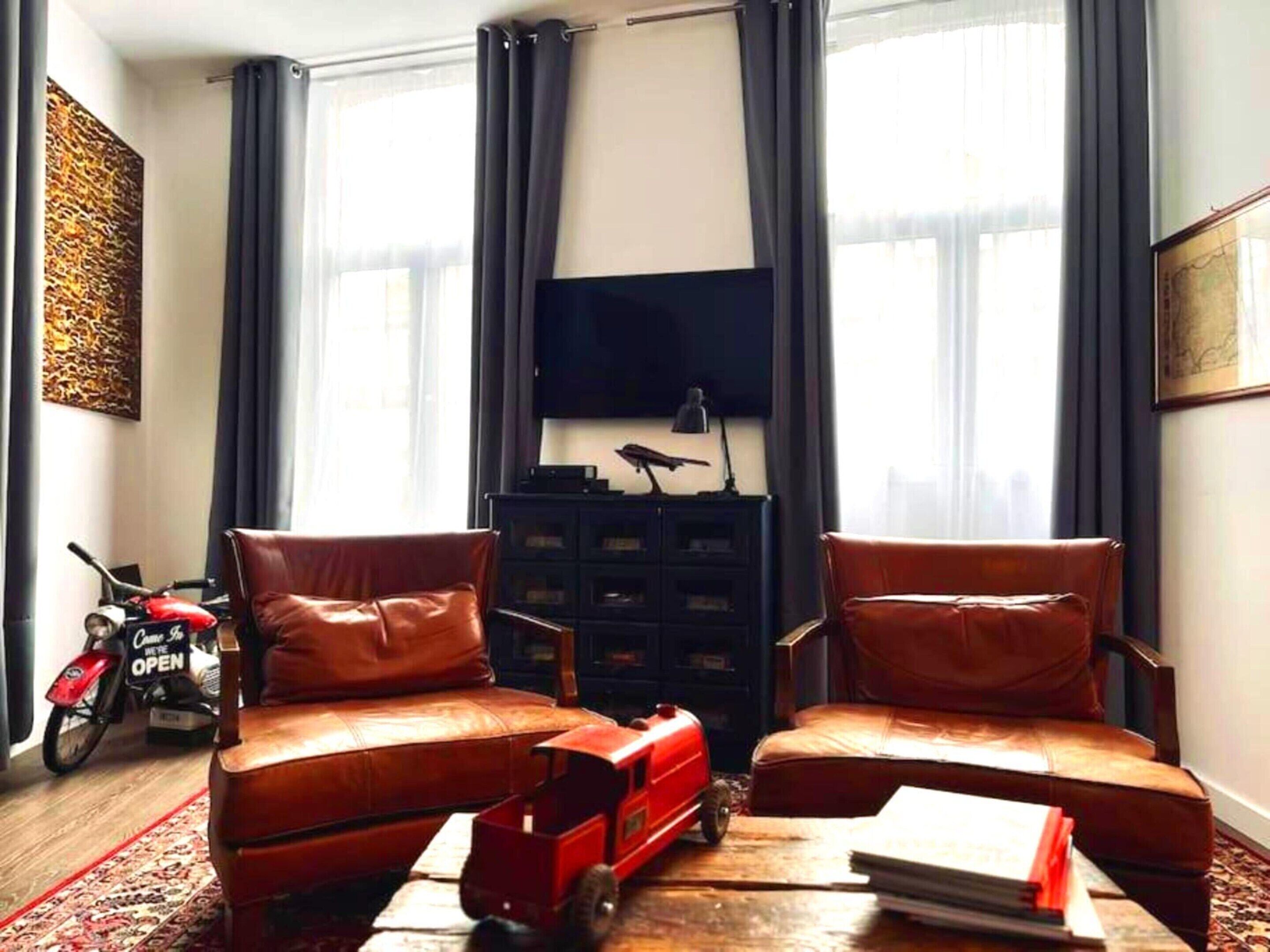 A living room with two leather sofas, a television, and a motorcycle in the background.