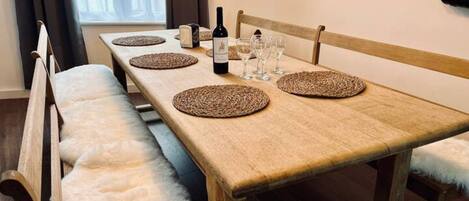 Una mesa de comedor dispuesta con manteles individuales, una botella de vino y copas.