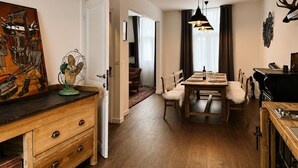 A dining area with a wooden table and chairs, a chandelier, and a painting on the wall. - Chic Vintage Apartment in Spa (Spa)